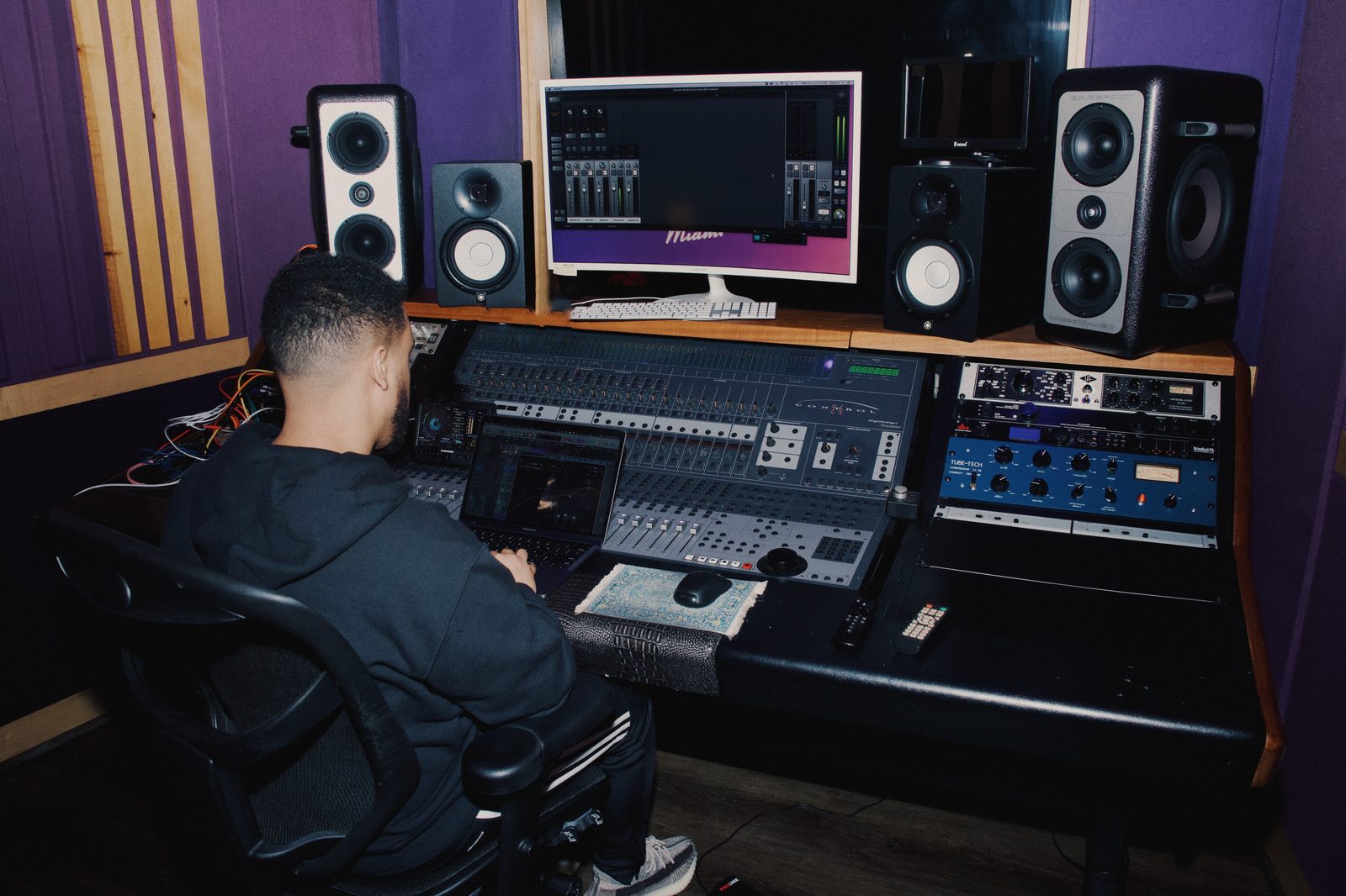 Luis Canción working at a studio mixing console surrounded by monitors and audio equipment